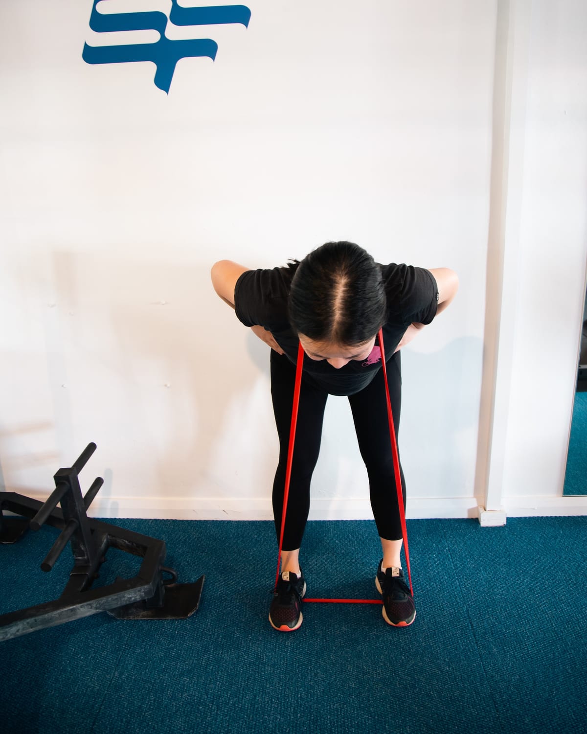 A woman performing a resistance band row in the SportsFit Five Dock gym