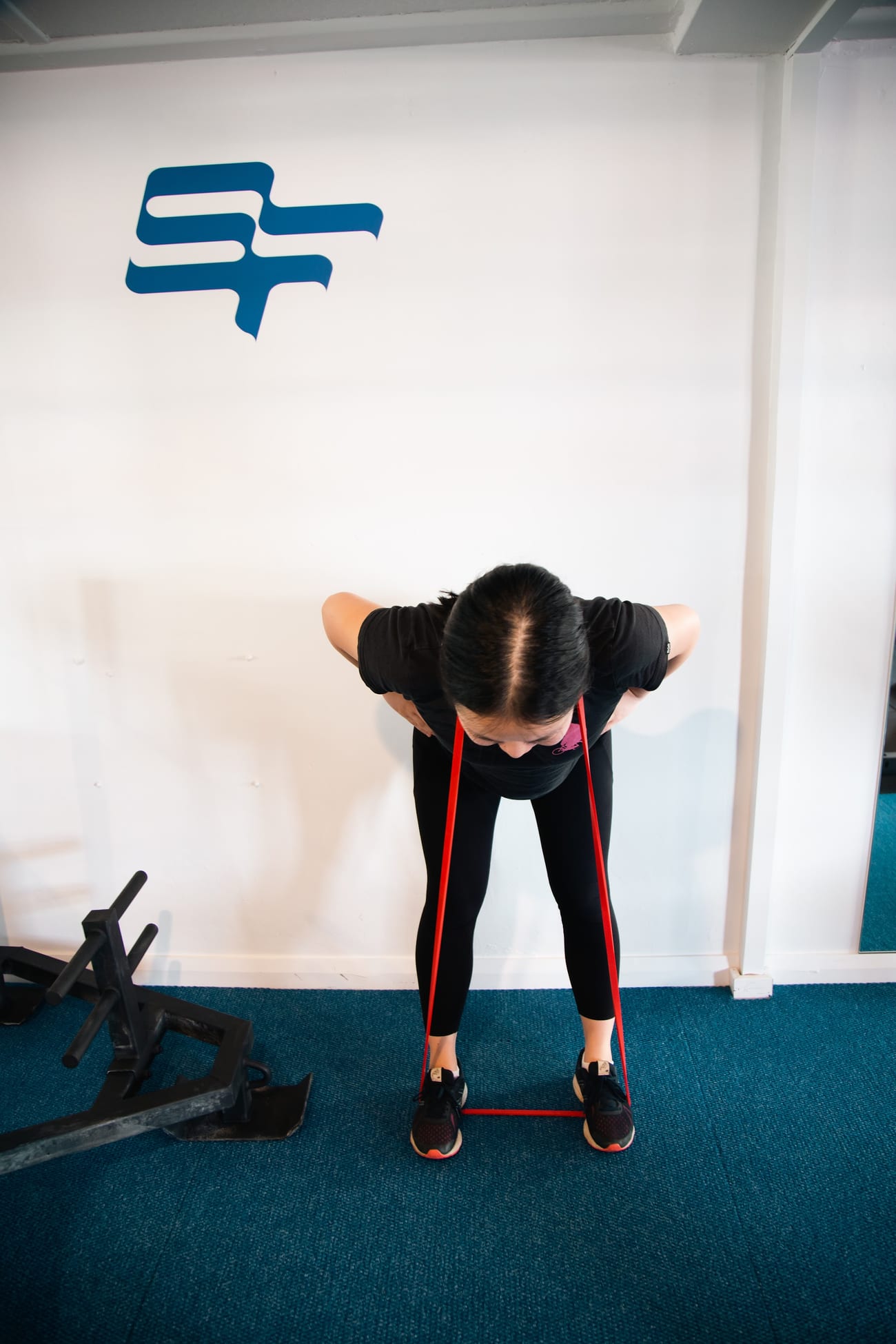 A woman performing a resistance band row in the SportsFit Five Dock gym